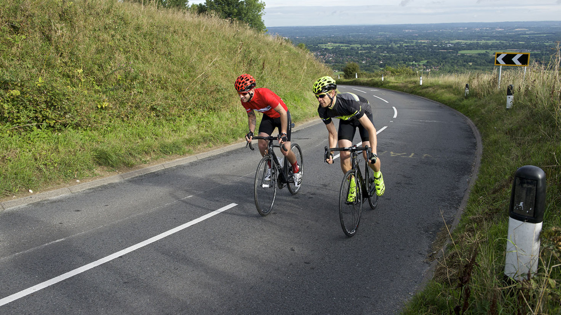 Two cyclists riding together on their Orro Bikes up a hill in the South of England on a warm summers day