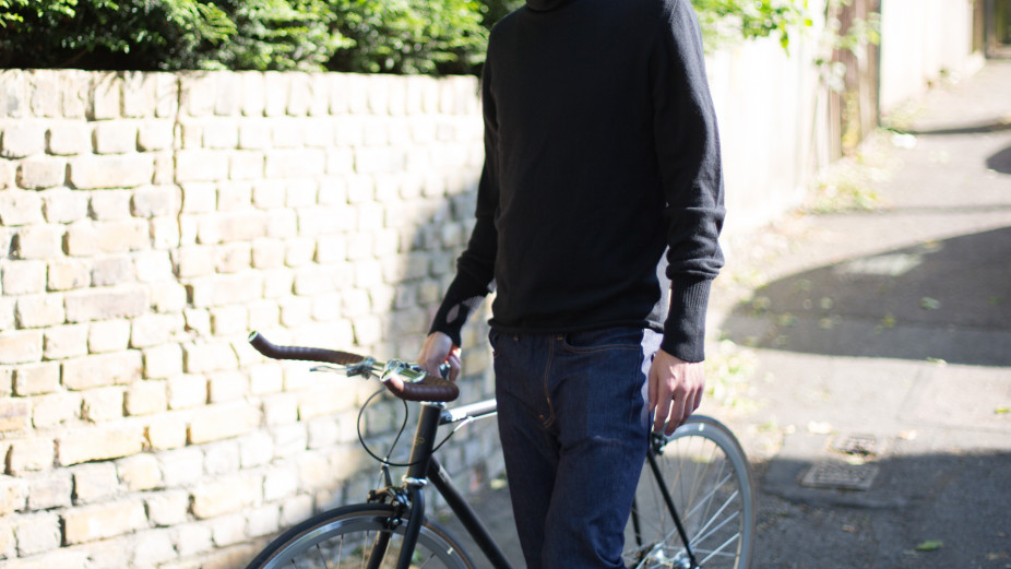 Body shot of a casual male cyclist wearing Fox Wilson clothing whilst holding onto his Orro FE Street road bike