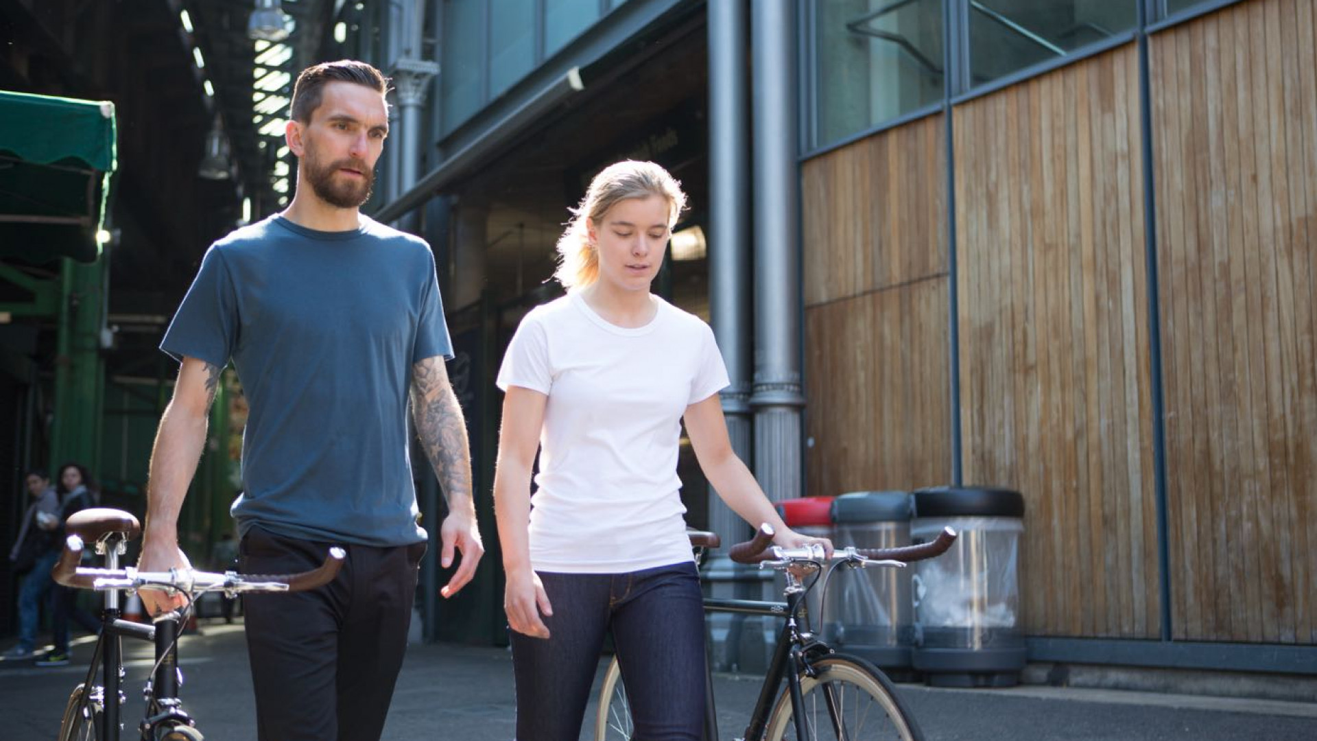 Two cyclists walking their Orro FE Street fixed gear bike whilst wearing Fox Wilson cycling clothing